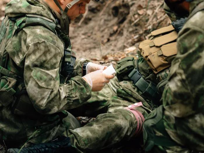 A soldier tending to the wounds of a fellow soldier in the field