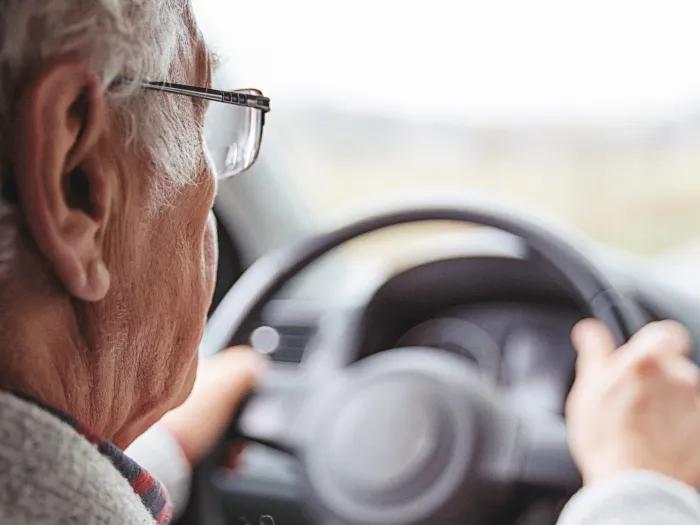 older man driving car behind wheel