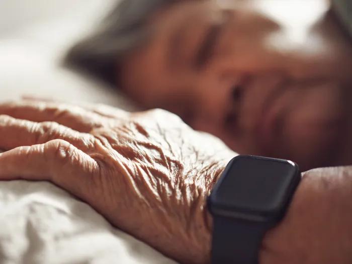 hand on pillow with smartwatch on wrist while person sleeps on pillow