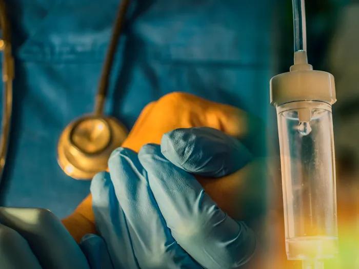 Physician holds the hand of a patient receiving cancer treatment, IV infusion.