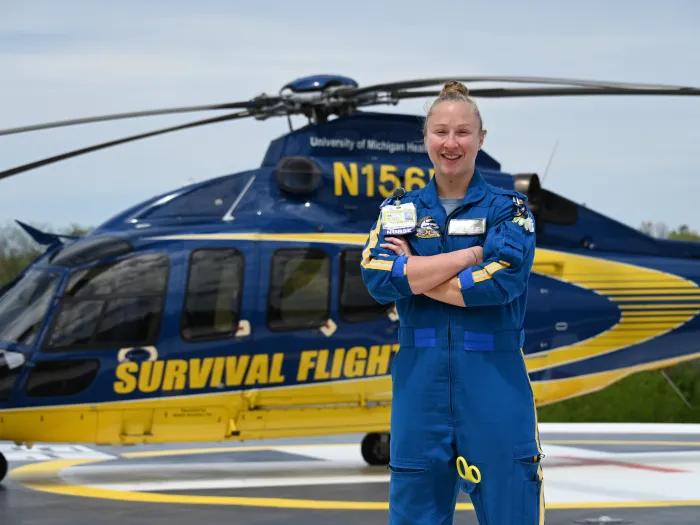 Flight nurse stands in front of a helicopter with arms crossed.