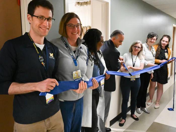 Staff gather to cut the ribbon at the grand opening of the new lactation room.