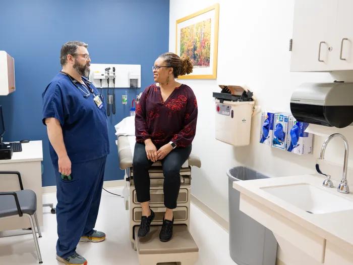 Photo of a male RN speaking with a female patient in a Michigan Clinical Research Unit exam room
