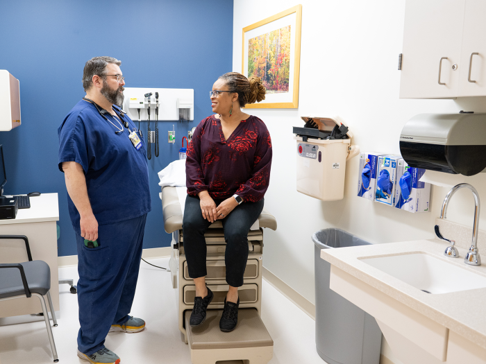 Photo of a male RN speaking with a female patient in a Michigan Clinical Research Unit exam room