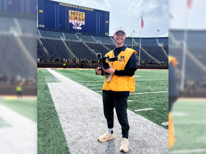 kid on field smiling in UM gear on UM football field