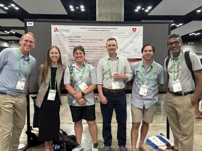 PAS attendees pose in front of a poster