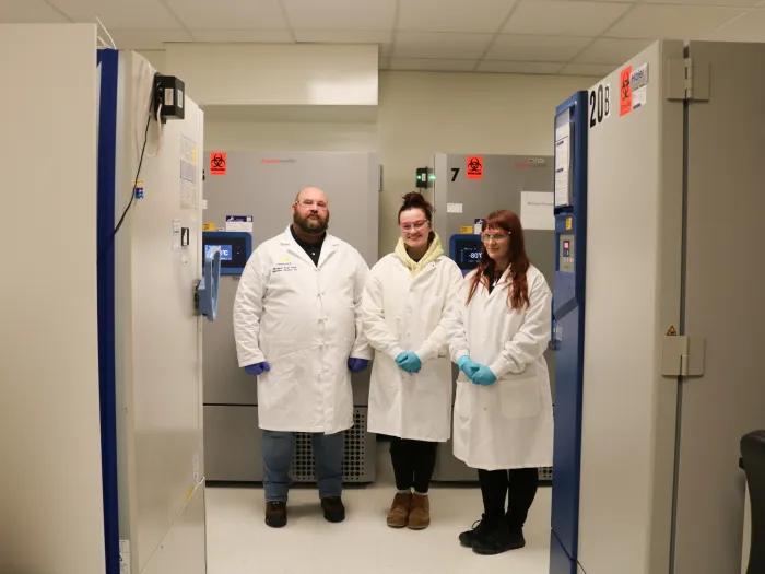 a group of three staff members stand in the brain bank space 