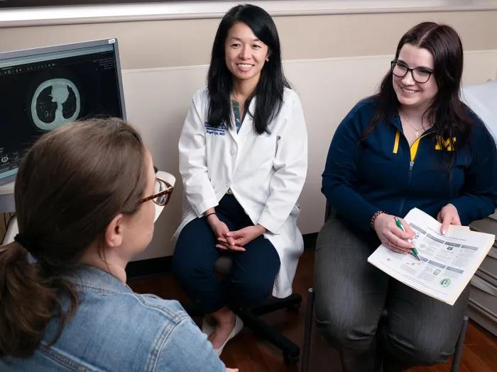 A patient, Angel Qin and nurse go over information about patient care