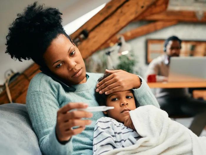 mom with sick child on phone checking tempature