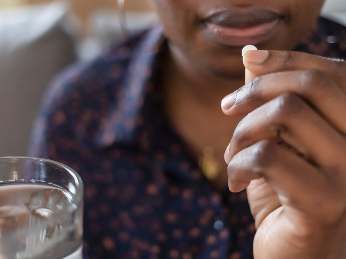 pill being taken close up with water near hand