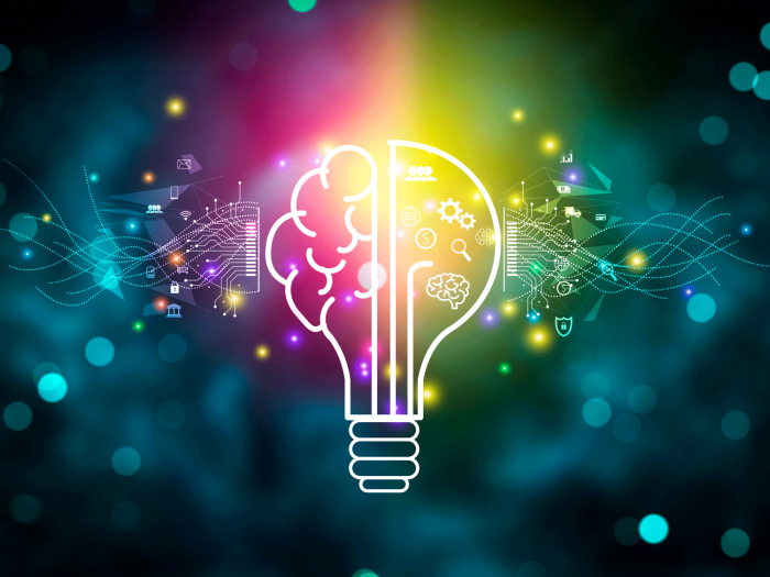 Colorful digital illustration of a glowing light bulb with a brain design inside it. The left half shows a stylized brain with circuit patterns, while the right half features icons such as gears, magnifying glass and graph. The background is dark with glowing bokeh and light trails, adding a dynamic, futuristic feel.