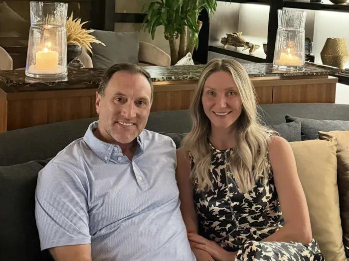 Danielle and David Risk seated comfortably together on a couch with an artistically decorated living space behind them.