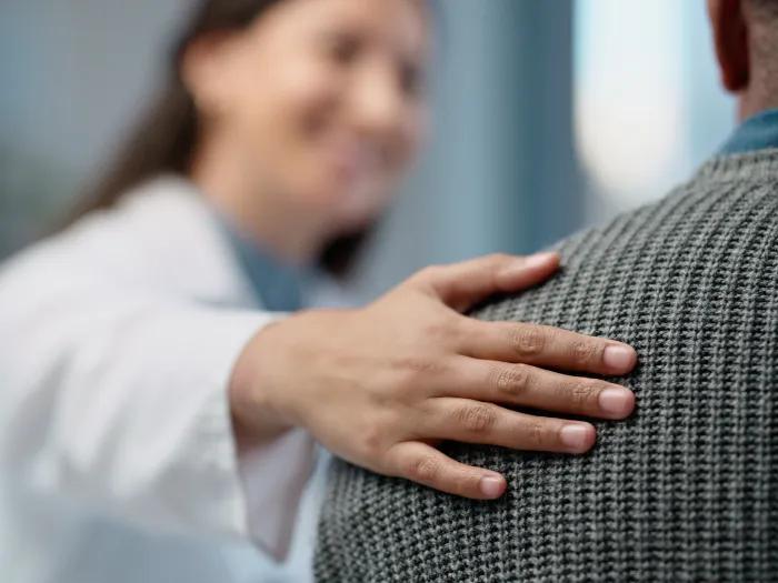 provider hand on back of patient caring blurred out 