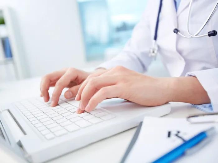 Photo of a female healthcare professional typing on a computer keyboard