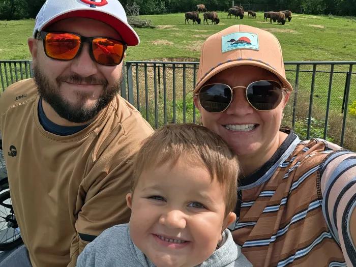 parents posing in selfie up close with kid in front of them