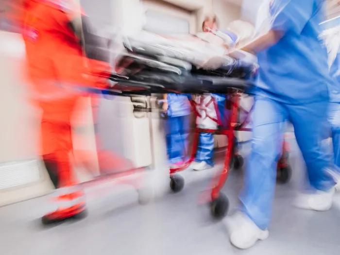 people rushing through the emergency room with bed