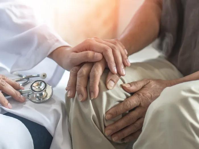 patient and doctor holding hands in comfort