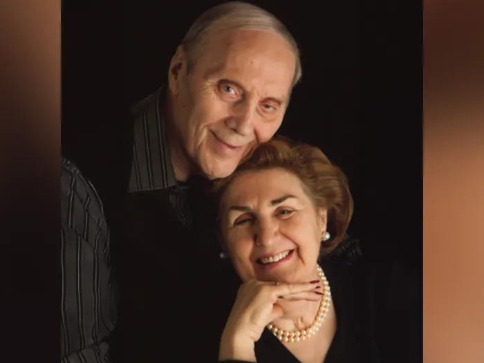 Portrait of Alexander and Gabriella Karp smiling and leaning in lovingly towards each other.