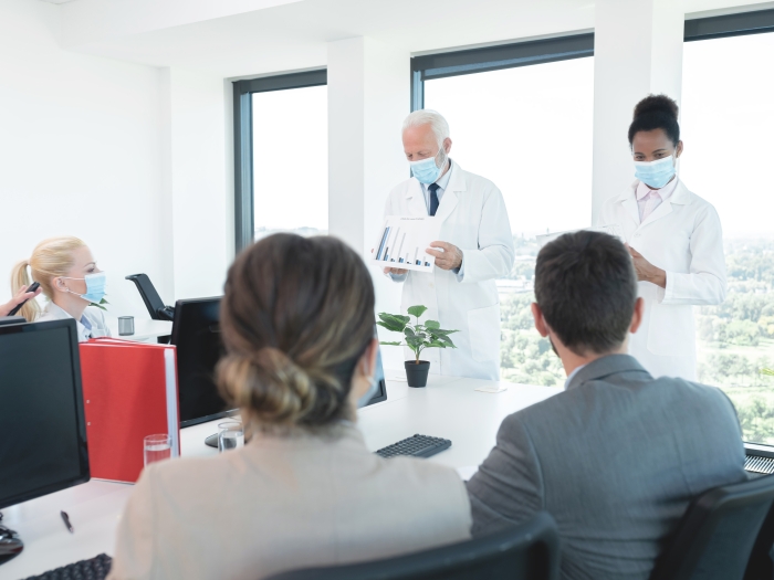 Photo of researchers presenting information to a room of people at a meeting table