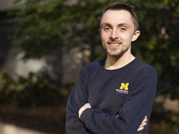 Headshot of Blake Hardin, a man wearing a Michigan Medicine blue long sleeved shirt outdoors