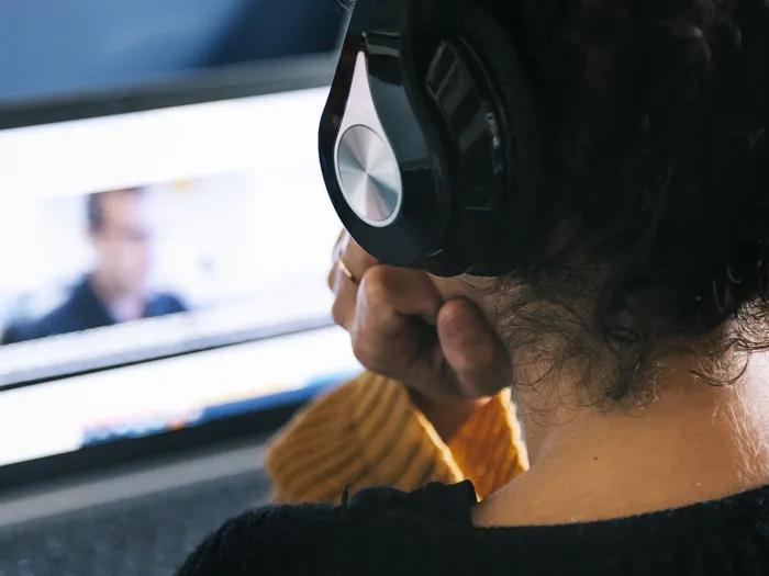 Person with headphones watching a laptop screen