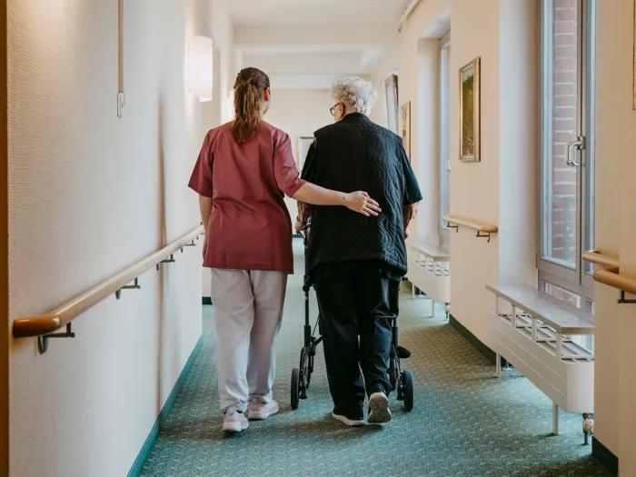 health care worker walking with older patient down hall