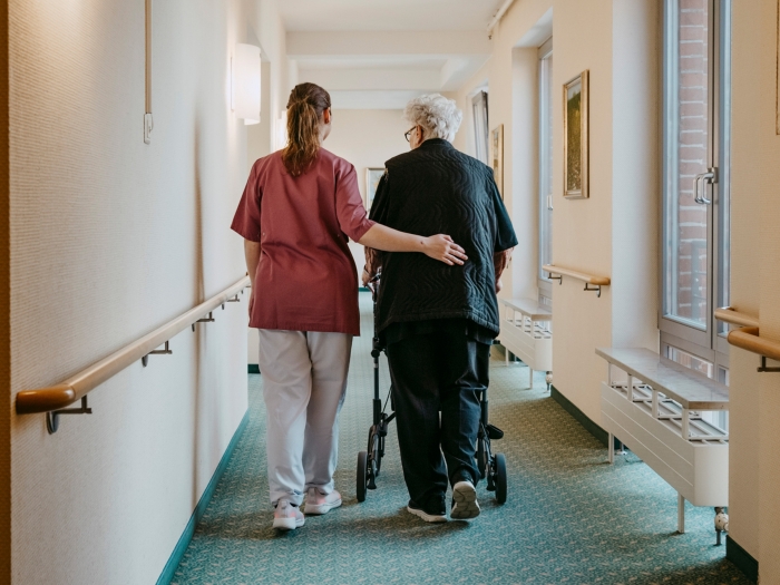 health care worker walking with older patient down hall