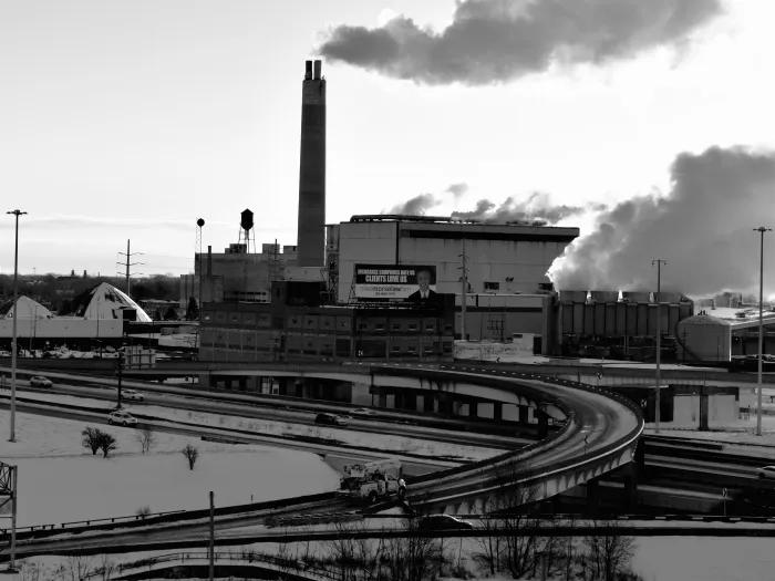 A black and white photo of a Detroit factory with a smokestack emitting air pollution