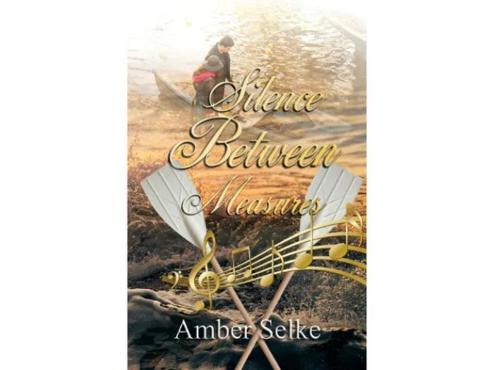 Book cover for "Silence Between Measures" by Amber Selke. The top half shows a person sitting in a wooden boat on a golden, shimmering river. The title, written in elegant gold script, overlays the scene. Two white boat oars cross in the foreground, interwoven with swirling gold musical notes. The author's name, Amber Selke, appears at the bottom in white.