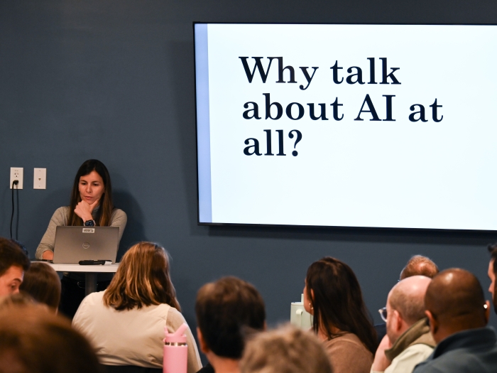 speaker in front of people seated at tables. the screen reads "why talk about AI at all?"