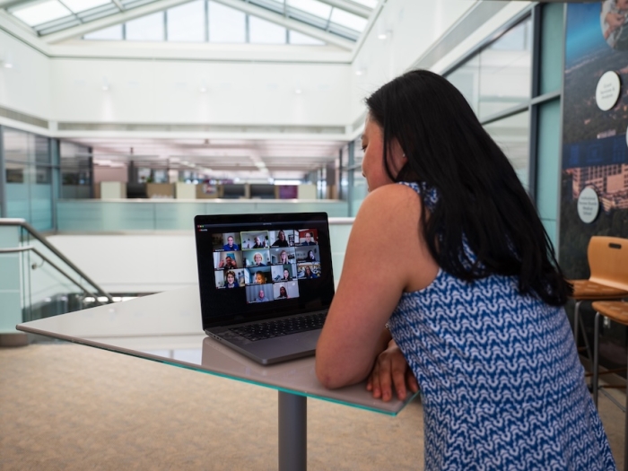Photo of woman sitting in front of a laptop looking at a Zoom meeting 