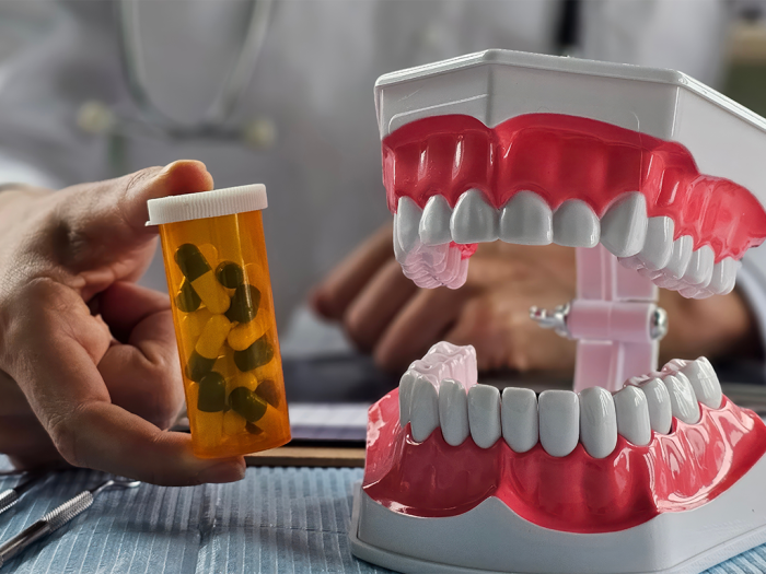 pill bottle next to fake mouth of teeth and gums