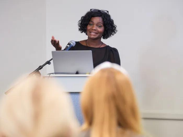 U-M patient, author, coach, and diabetes advocate Safiyah Basir speaks at a CDI Community Seminar, presenting to attendees from behind a podium and microphone.