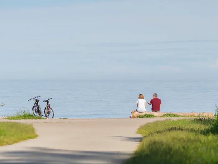 couple in distance with bikes by water and green 