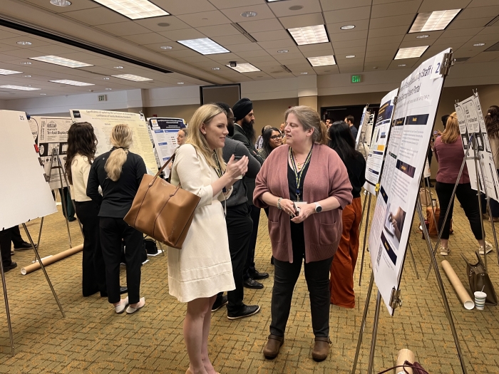 Two women discuss a poster at a conference