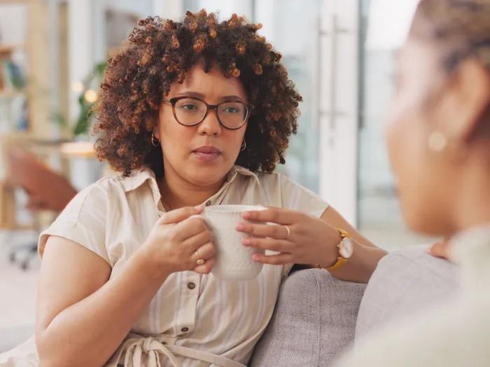 Woman holding coffee cup and talking to another woman