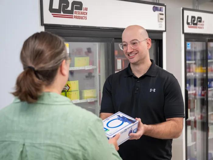 A BRCF Research Store staff member hands a product to a customer.