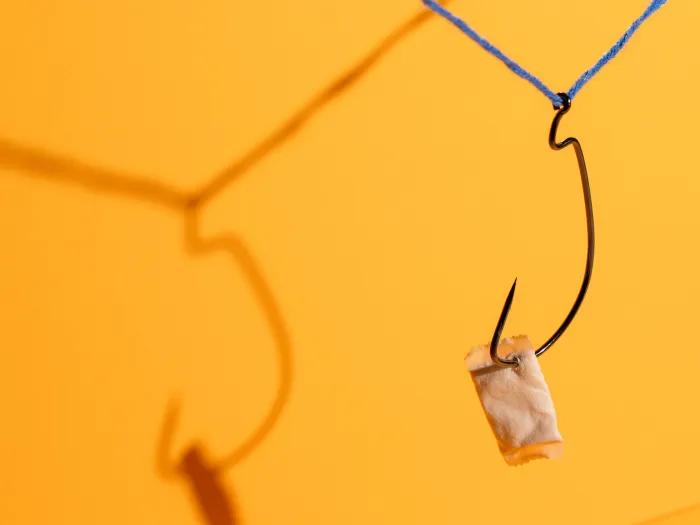 nicotine packet hanging from hook orange background