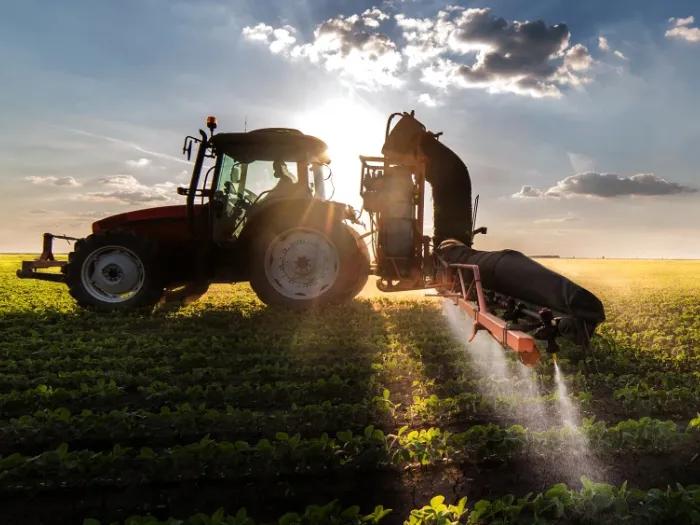 a tractor spraying pesticides on a planted field