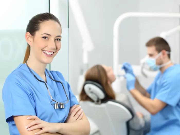 woman posing and smiling for a picture outside of a dental room