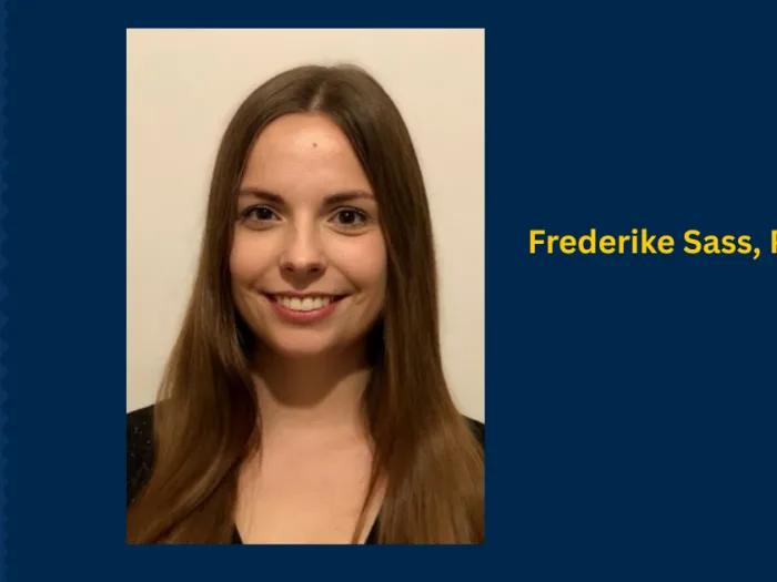 Headshot of person with long brown hair smiling wearing a black top. The image is framed by a larger dark blue background with the text Frederik Sass, PhD.