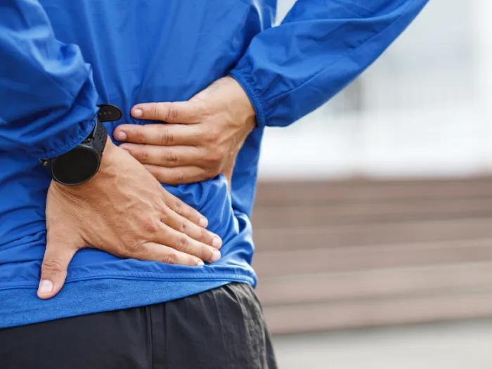 Close-up of person's hands on their lower back
