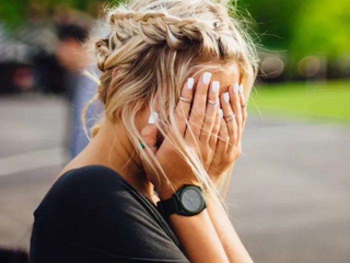A woman hides her face behind her hands