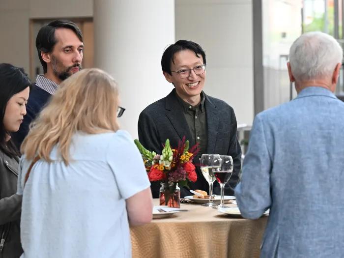 Yunlu Zhu smiles at a table with colleagues