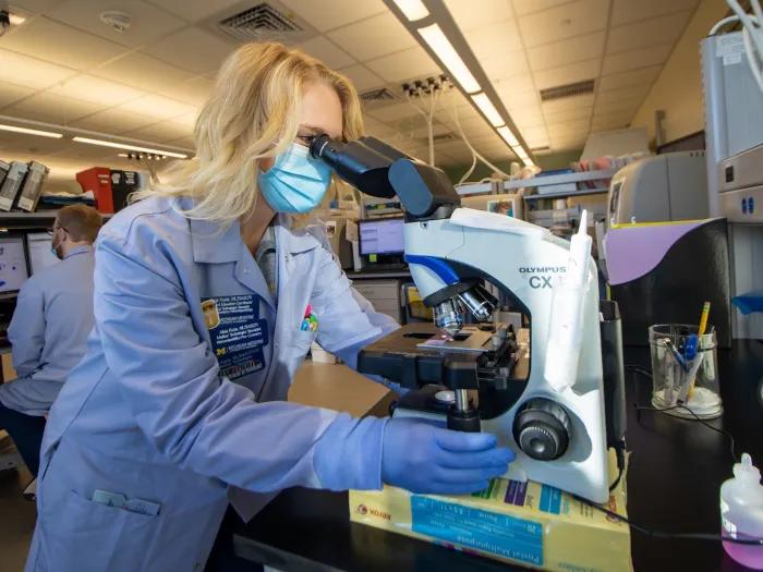 researcher at microscope in a lab
