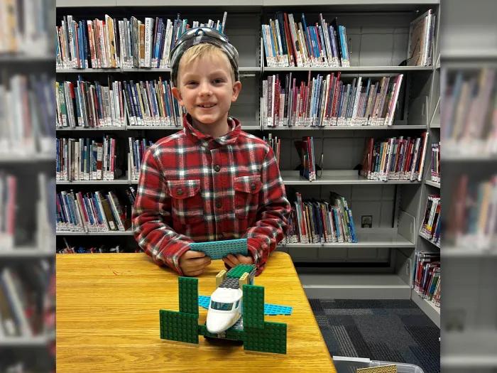 little boy at table smiling in library 