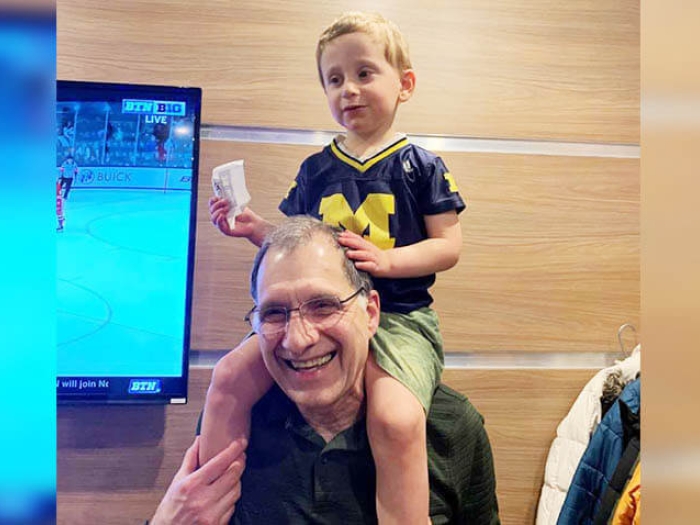 Grandpa with grandson on shoulders near a TV