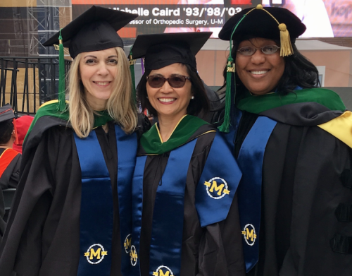 three graduates smiling at the camera