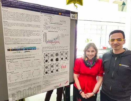 Hamadi Madhi, PhD poses with Sofia Merajver, MD, PhD next to his research poster