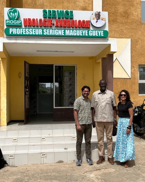 Michigan Medicine faculty outside a hospital entrance beneath a sign reading ‘Service Urologie-Andrologie — Professeur Serigne Maguaye Gueye.